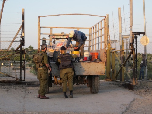 Soldater kontrollerar en bondes last på ockuperat område på Västbanken i Palestina.